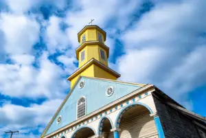 Blau-gelbe Holzfassade und Turm der Kirche Nuestra Señora del Rosario in Chonchi auf Chiloé