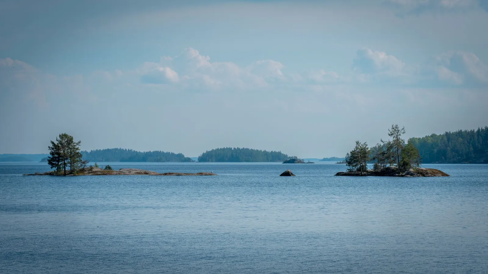 Kleine bewaldete Felseninseln im ruhigen Saimaa-See in Finnland